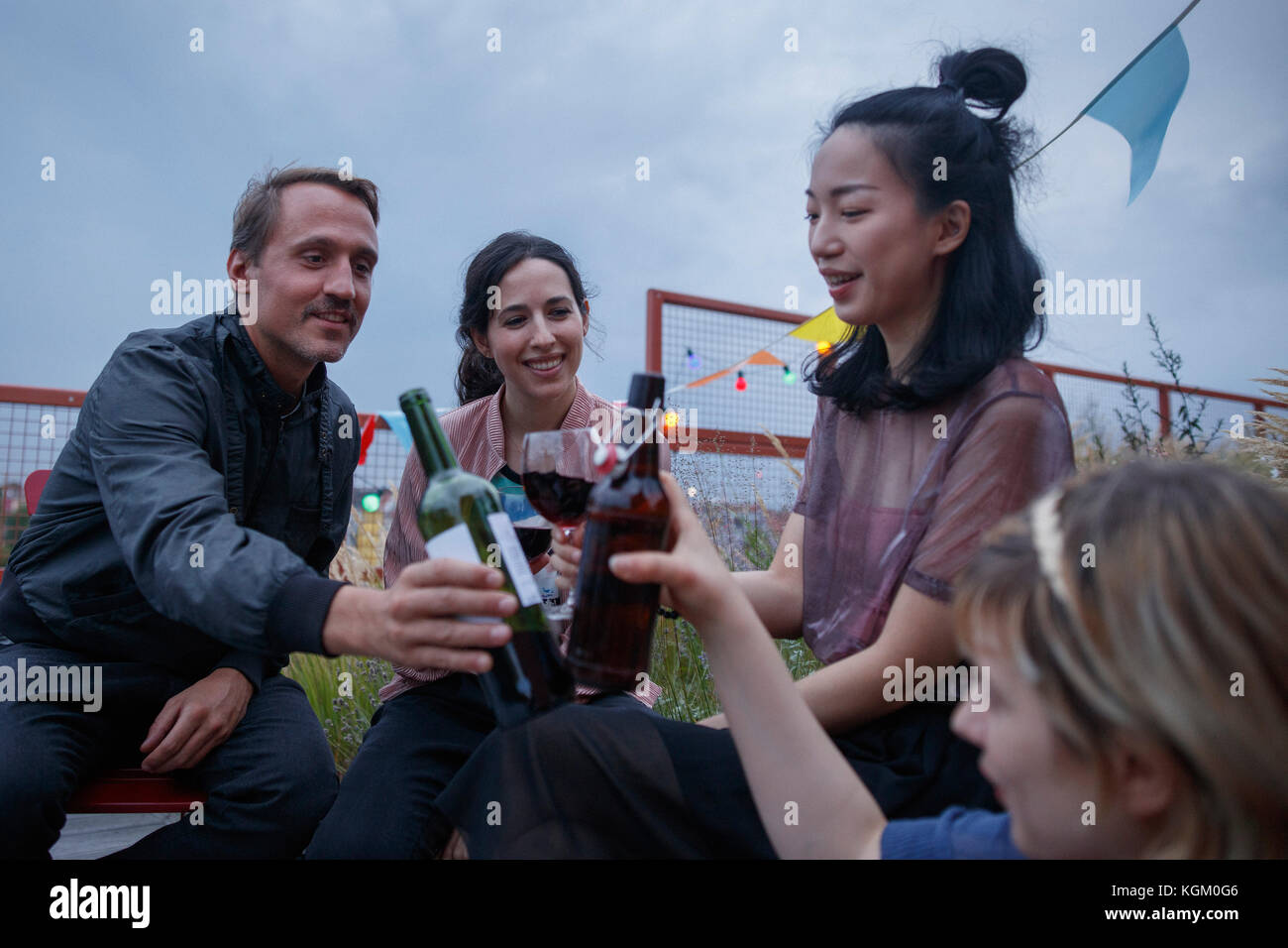 Multi-ethnischen Freunde toasten Wein Flaschen während der Party auf der Terrasse Stockfoto