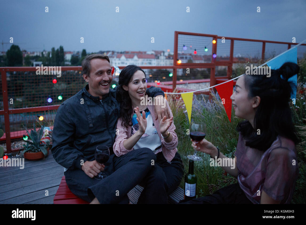 Glückliches Paar mit Freundin holding Wein auf der Terrasse Stockfoto