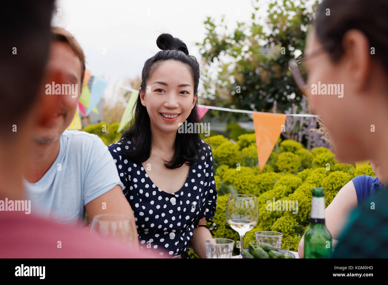 Glückliche junge Frau sitzt mit Freunden auf der Terrasse Stockfoto