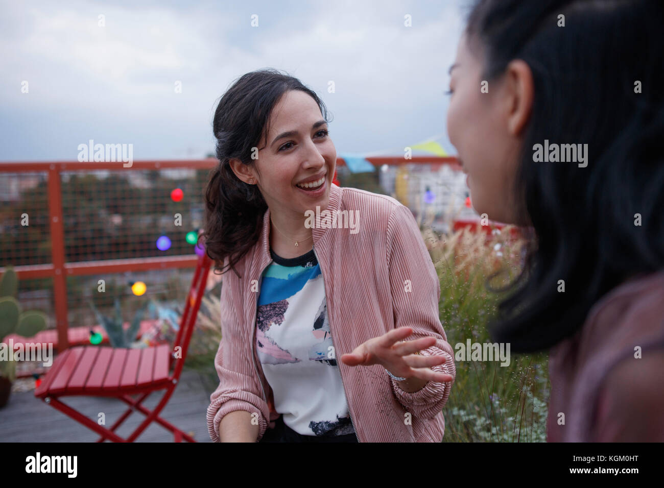 Glückliche Frau im Gespräch mit Freundin beim Sitzen auf der Terrasse Stockfoto
