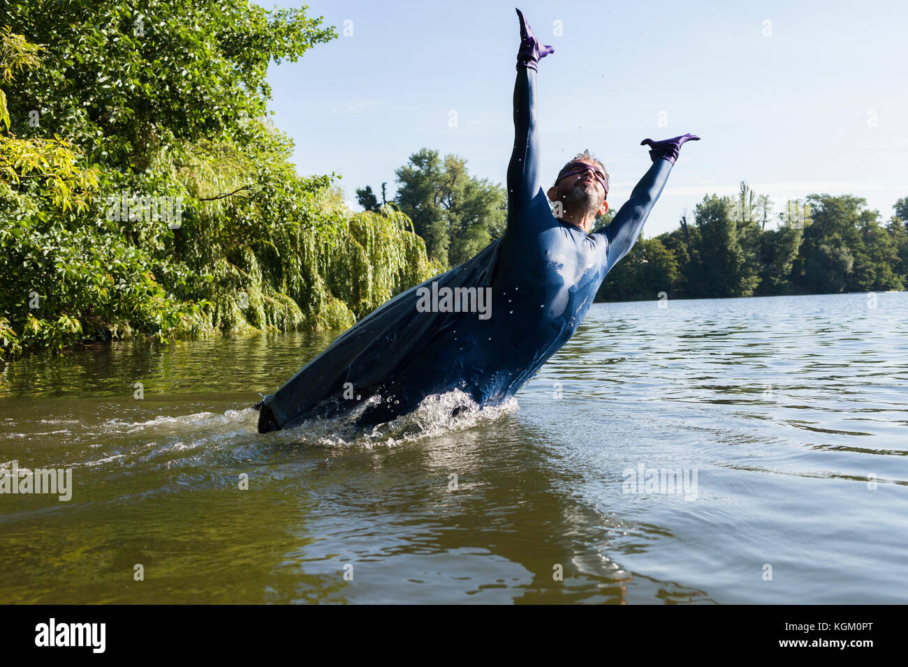 Reifen Superhelden springen mit Waffen in Fluss gegen Himmel angehoben Stockfoto