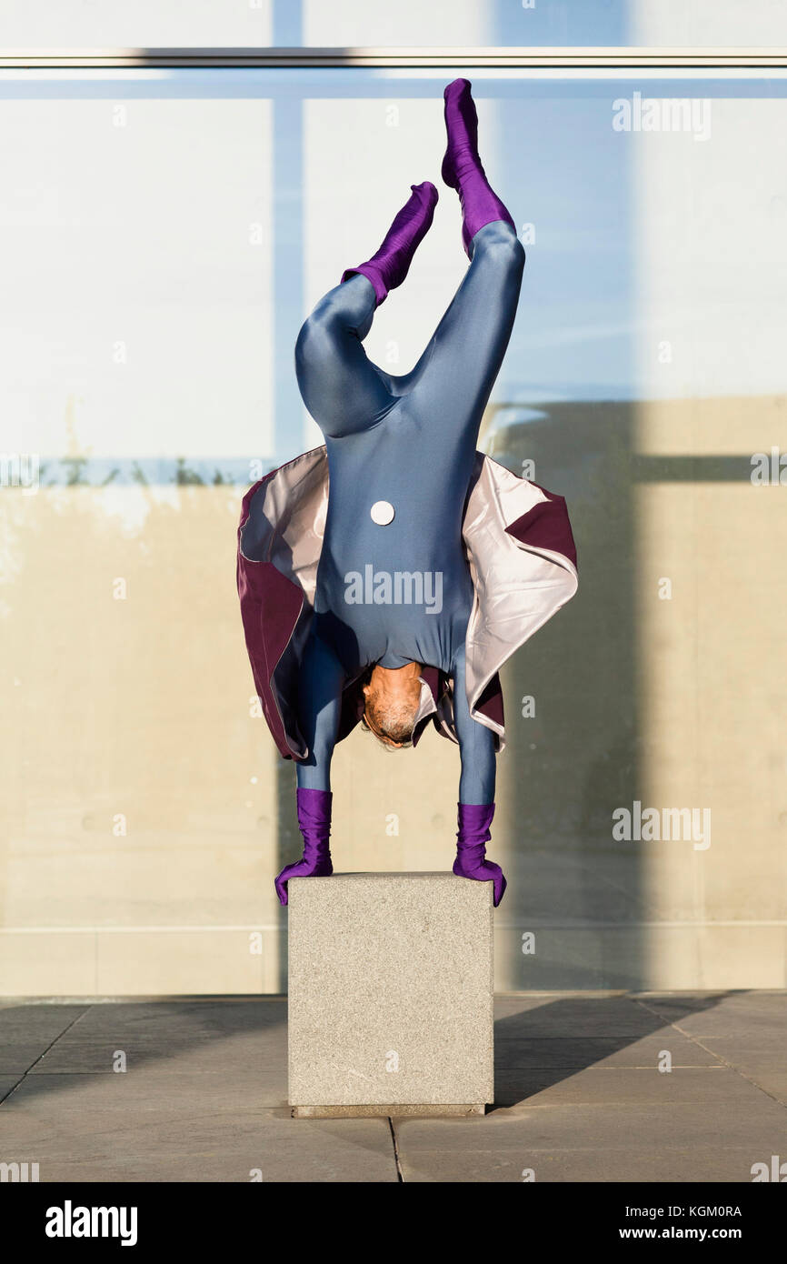 Superhelden macht Handstand auf Beton gegen die Glaswand Stockfoto
