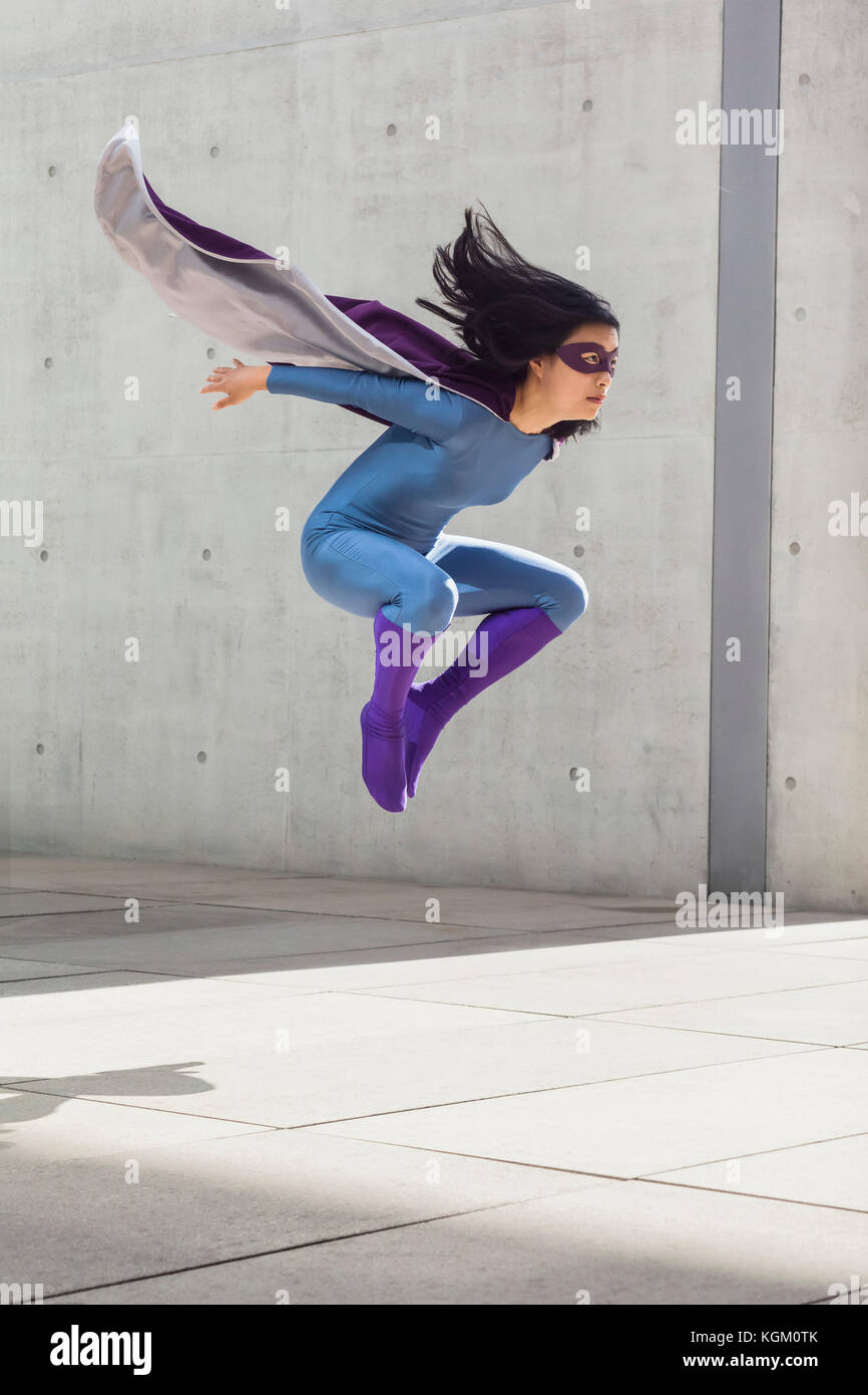 Weibliche Superheld Mitte schwebend-Luft gegen die Wand Stockfoto