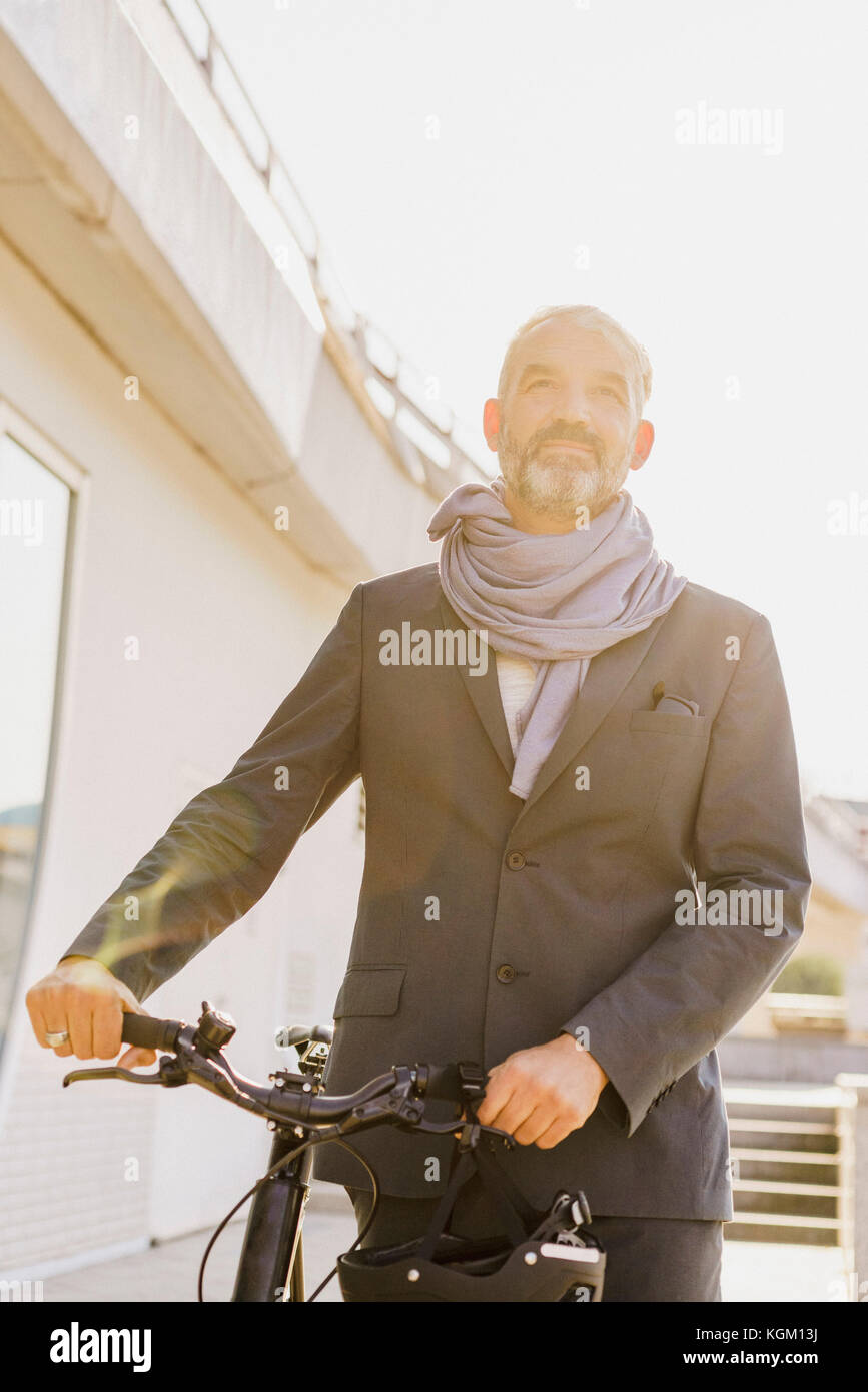 Low Angle View der Geschäftsmann mit Fahrrad in der Stadt an einem sonnigen Tag Stockfoto