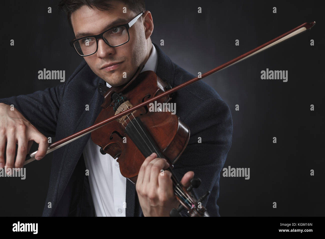 Schöner Mann tragen formals spielen Geige auf schwarzem Hintergrund Stockfoto