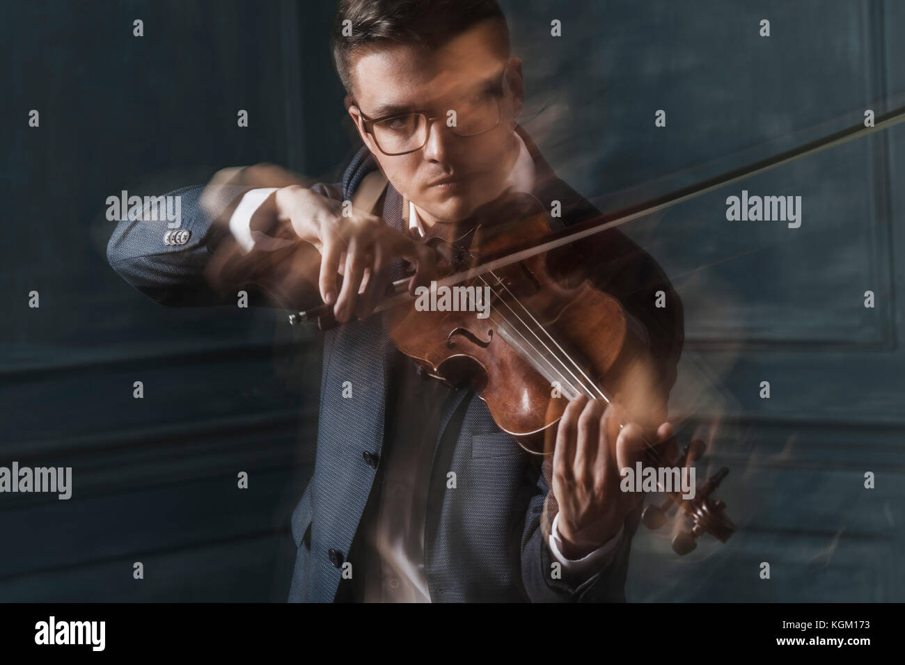 Verschwommene Bewegung der zuversichtlich Geiger spielen Geige gegen die Wand Stockfoto