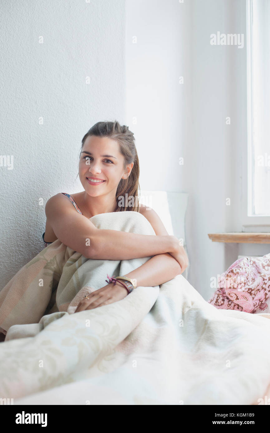 Porträt der schönen Frau sitzend mit Decke auf dem Bett zu Hause. Stockfoto