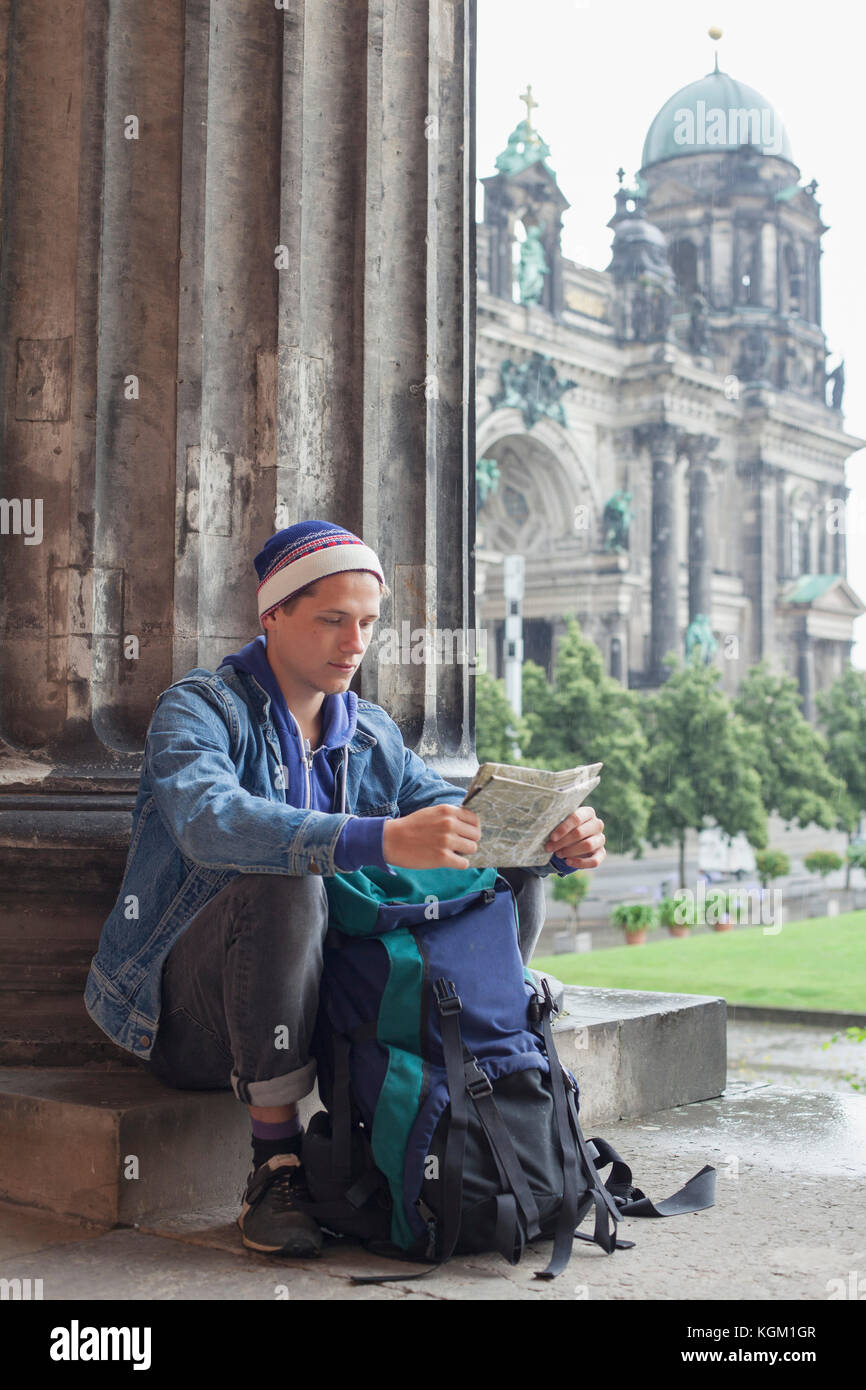 Junge männliche Touristen sitzen mit Karte bei Altes Museum gegen Berliner Dom, Deutschland Stockfoto