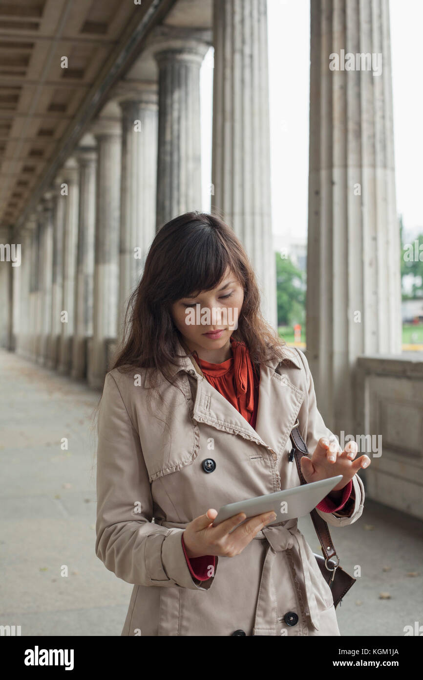 Junge Frau mit digitalen Tablet beim Gehen in Flur, Berlin, Deutschland Stockfoto