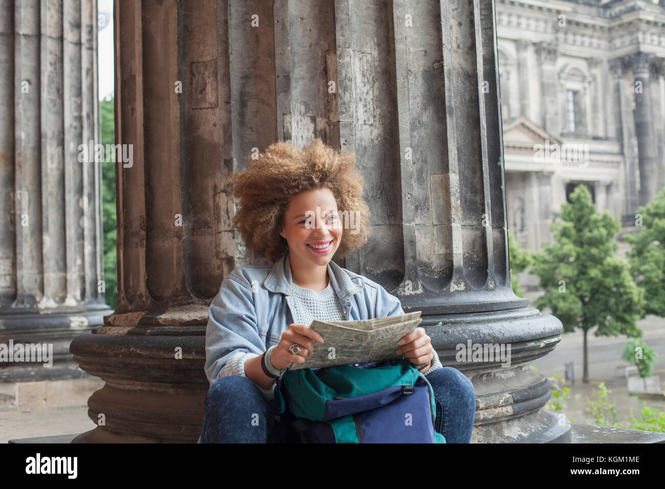 Portrait von lächelnden jungen Afro weibliche Touristen sitzen mit Karte gegen Spalte Altes Museum Stockfoto