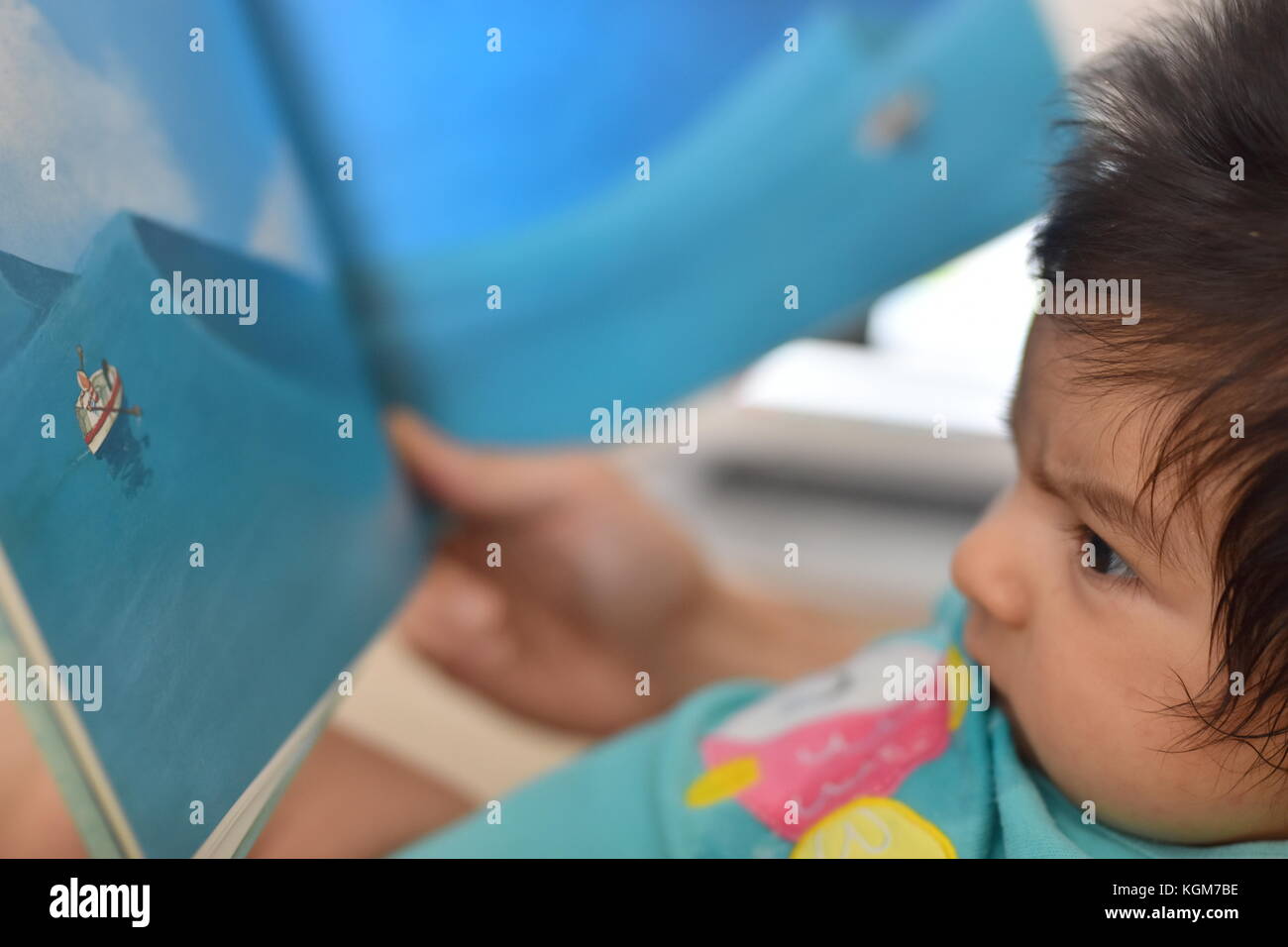 Neugeborenes Baby aufmerksam lesen Kinderbuch mit Illustrationen Stockfoto