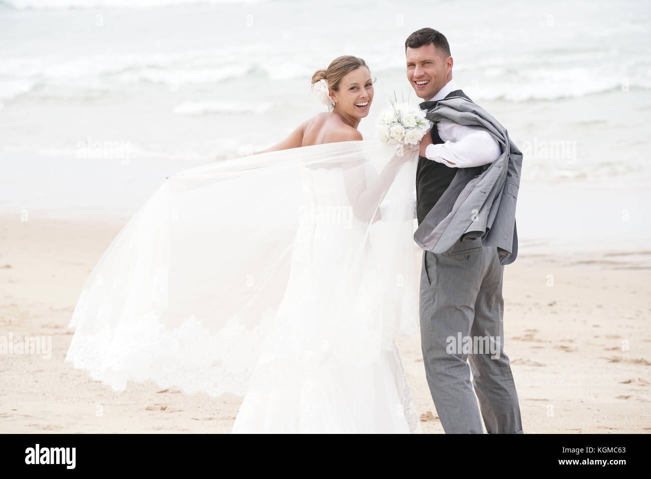 Fröhlich frisch verheiratete Ehepaar zu Fuß am Strand Stockfoto