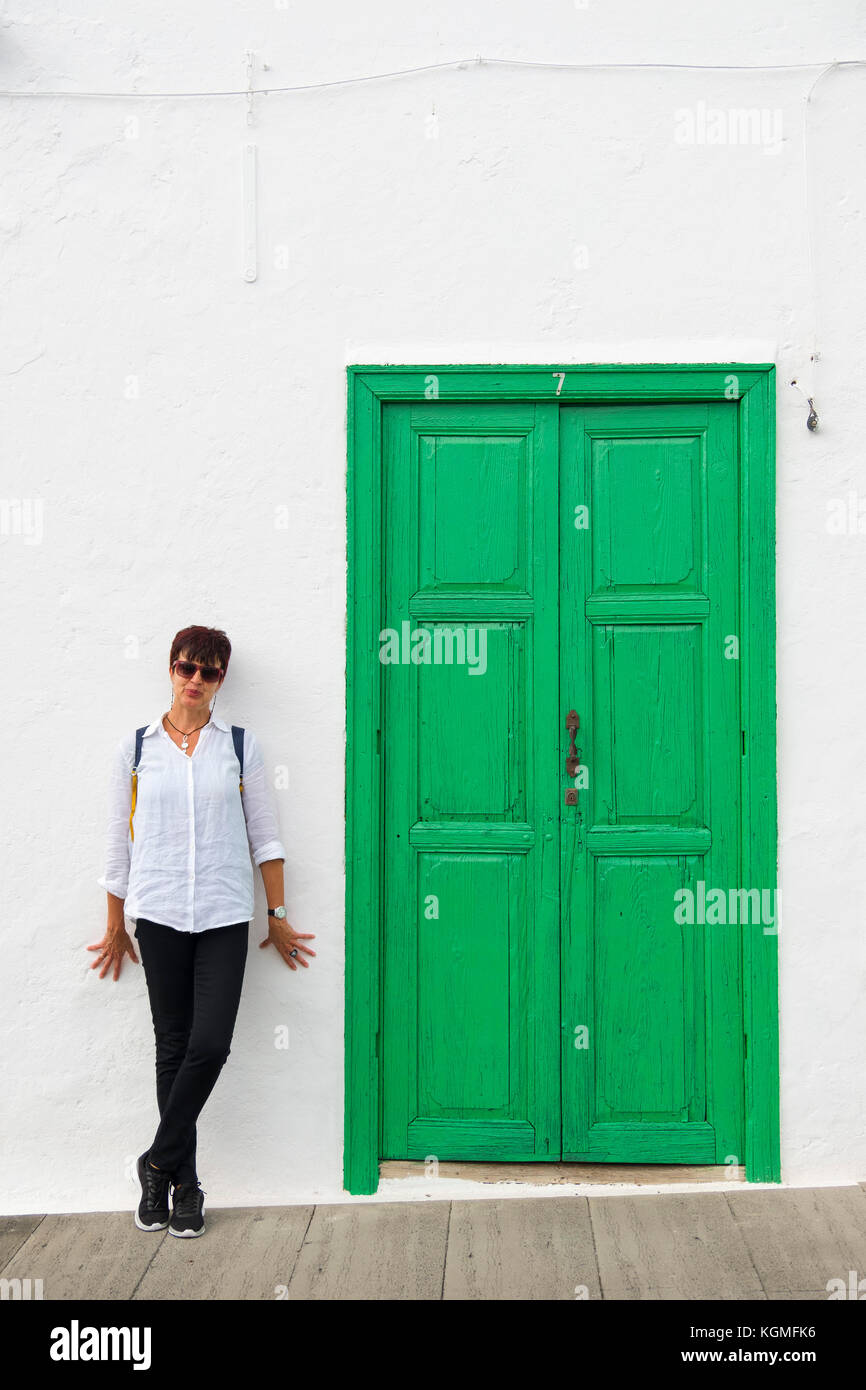 Straßenszene, Frau an einer weißen Wand und grüner Tür. Teguise, Lanzarote Island, Kanarische Inseln. Spanien Europa Stockfoto
