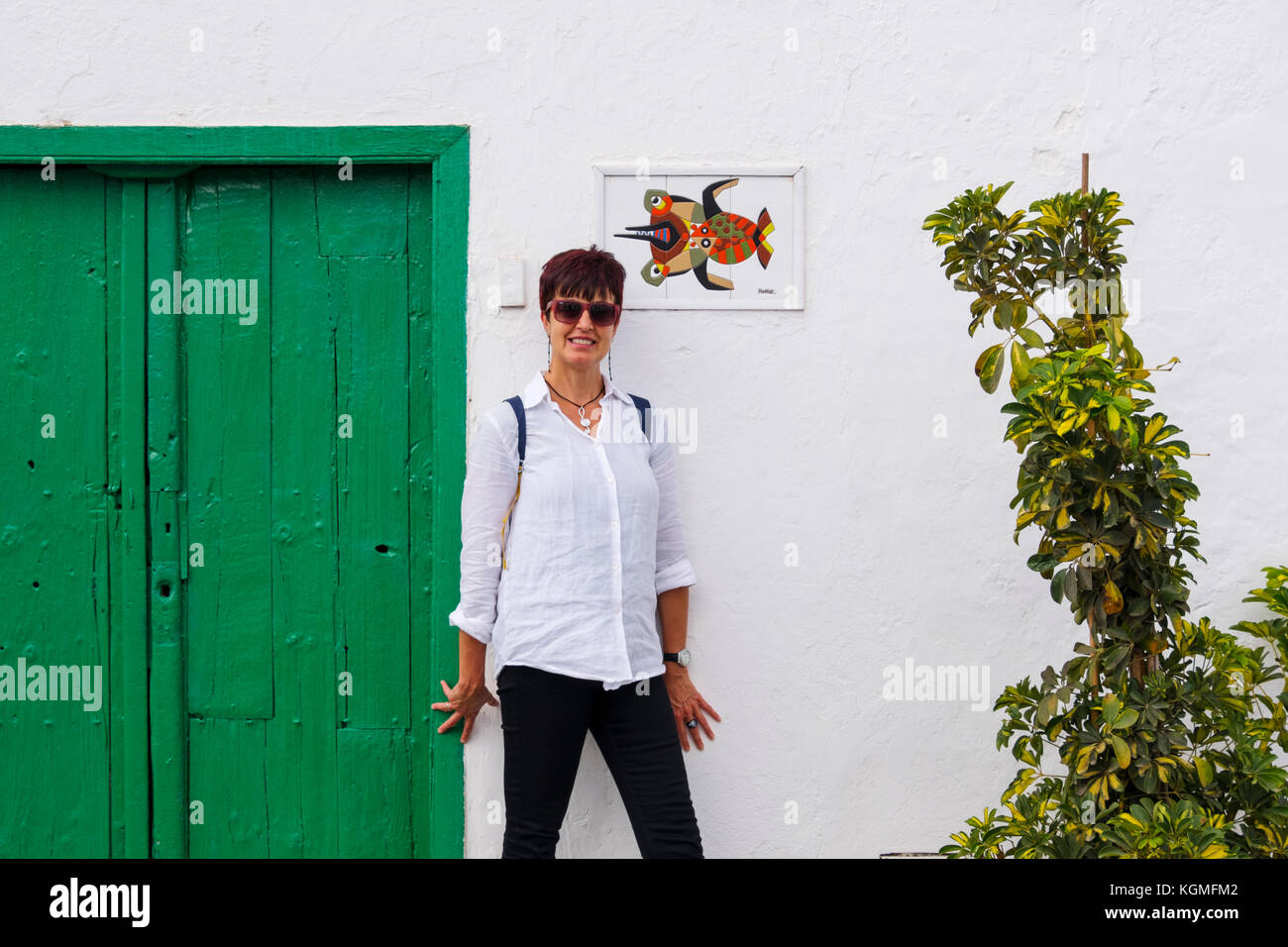 Straßenszene, Frau an einer weißen Wand und grüner Tür. Teguise, Lanzarote Island, Kanarische Inseln. Spanien Europa Stockfoto