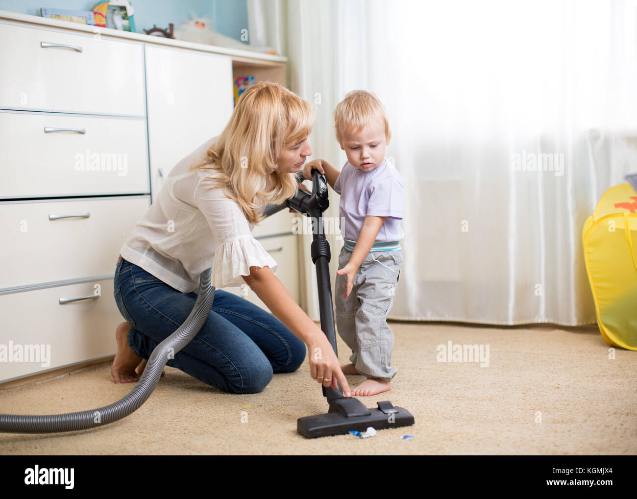 Reinigung der Zimmer zusammen - Mutter und ihrem Kind Sohn mit Staubsauger absaugen Stockfoto