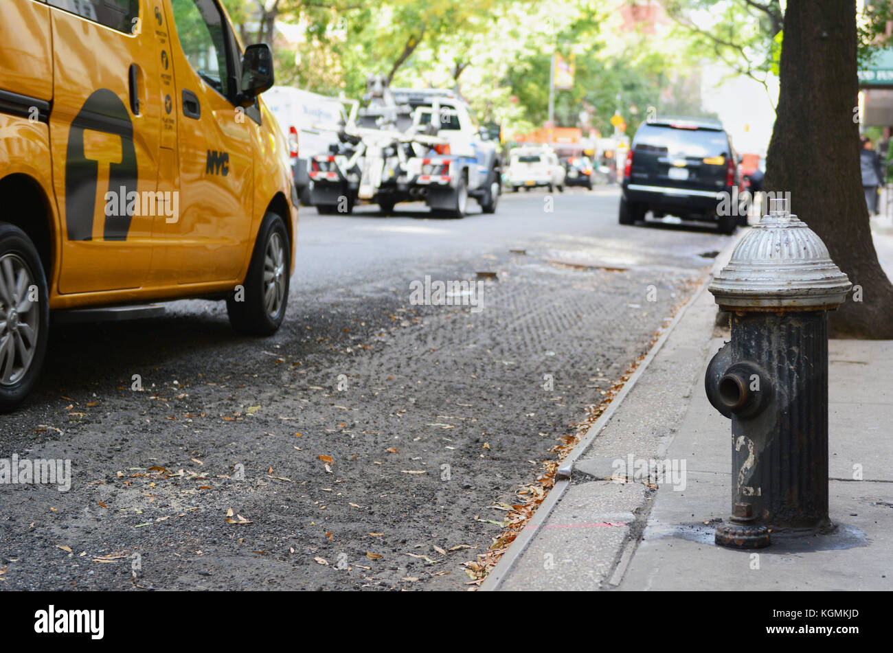 Black Fire Hydrant am Rande eines new york city Sidewalk. Ein gelbes Taxi und Polizei Abschleppwagen sind unter der Straße fahren. Stockfoto