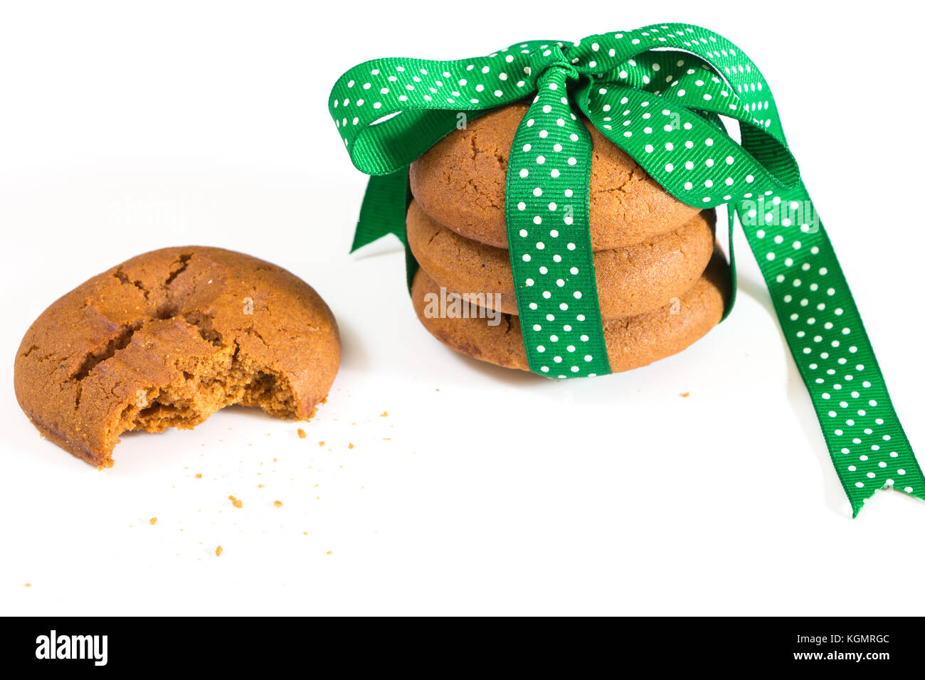 Cookies mit grünem Band und gebissen Cookie mit krümel gebunden, auf weißem Hintergrund. Stockfoto