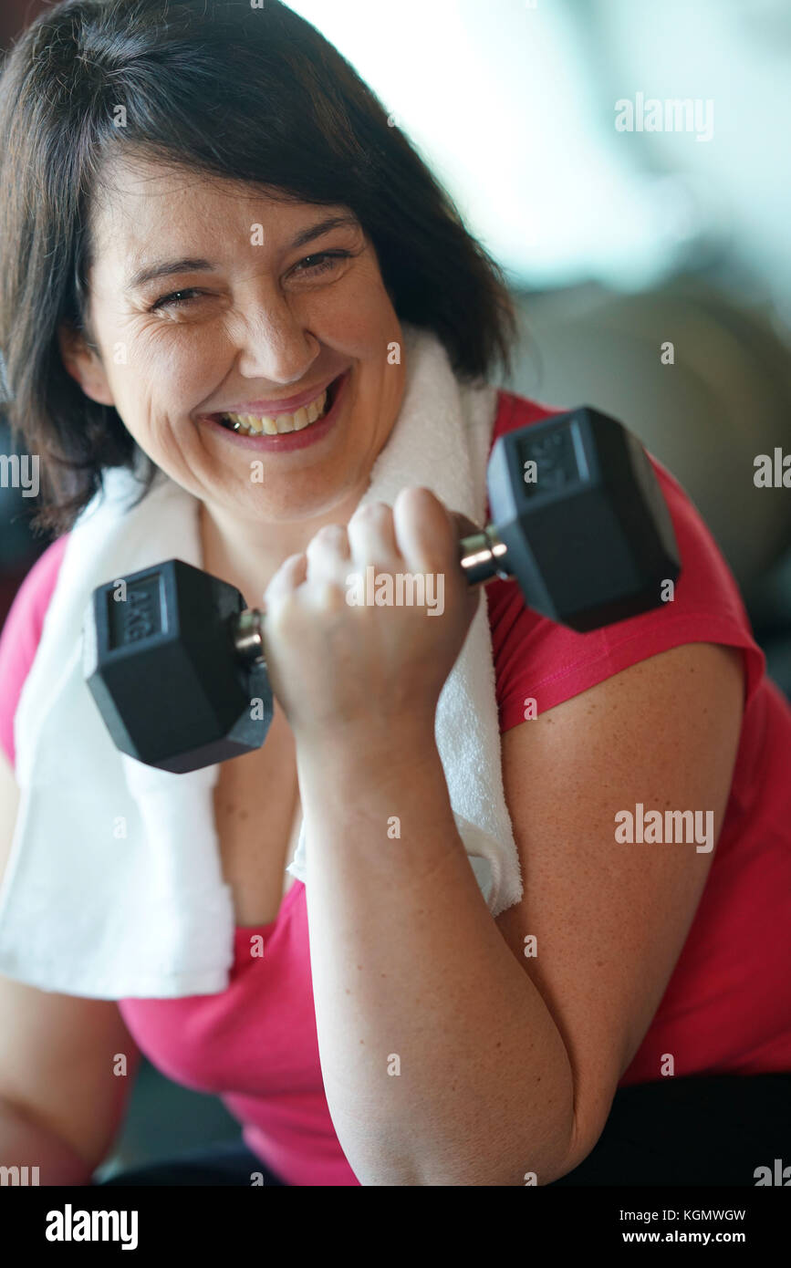 Übergewichtige Frau im Fitnessstudio Hanteln Stockfoto