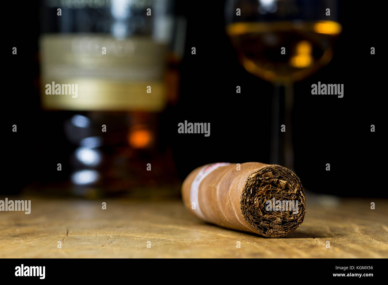 Nahaufnahme von Stillleben mit einer Zigarre, eine Flasche Alkohol und einem Glas Whiskey auf einem alten Holztisch, mit einem unscharfen Hintergrund Stockfoto