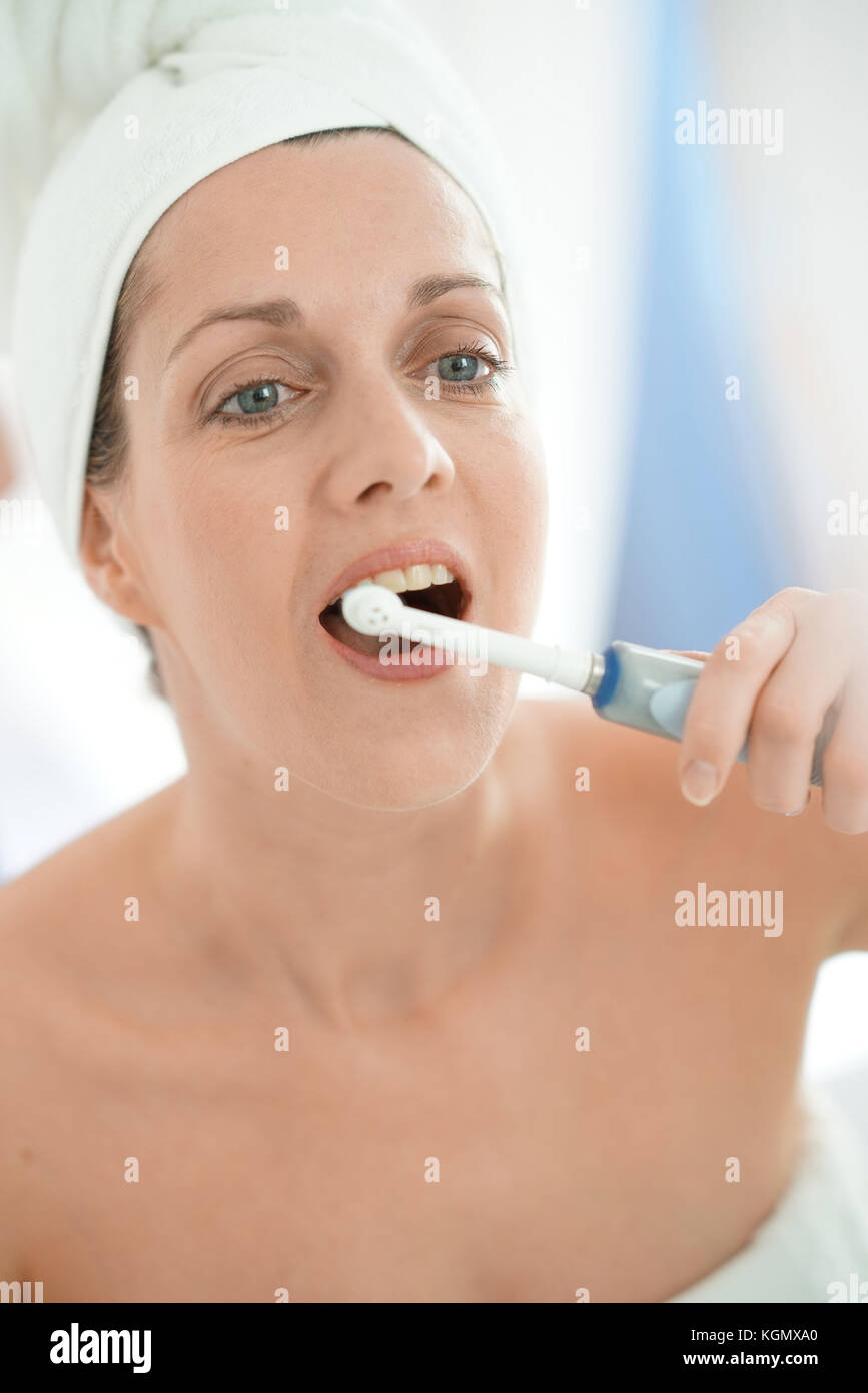 Frau im Badezimmer die Zähne putzen mit elektronischen Zahnbürste Stockfoto