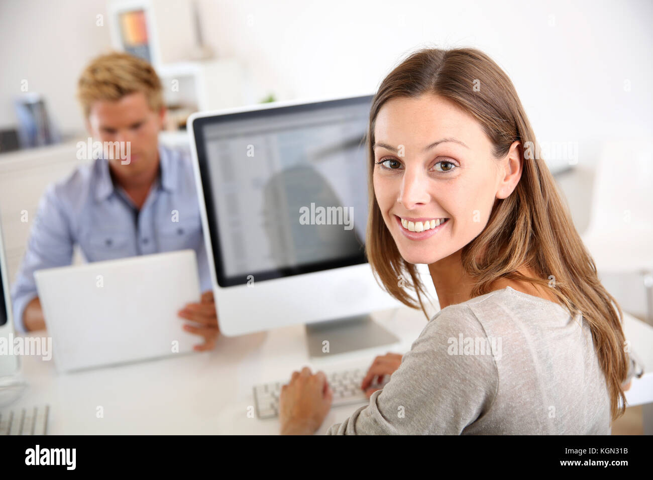 Portrait von lächelnden Büroangestellter vor Desktop Stockfoto