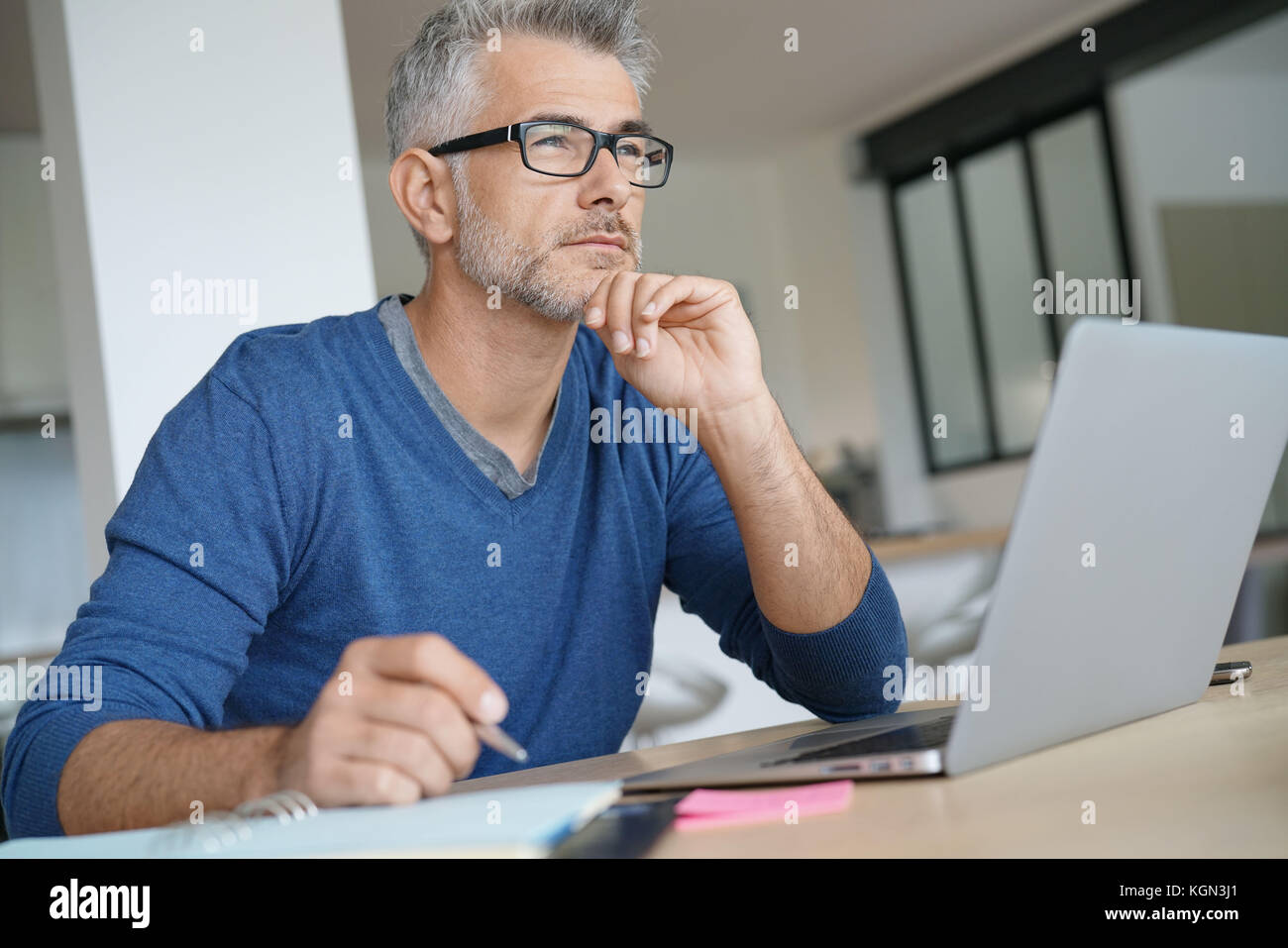 Mann mittleren Alters Arbeiten am Laptop-nachdenklichen Blick Stockfoto