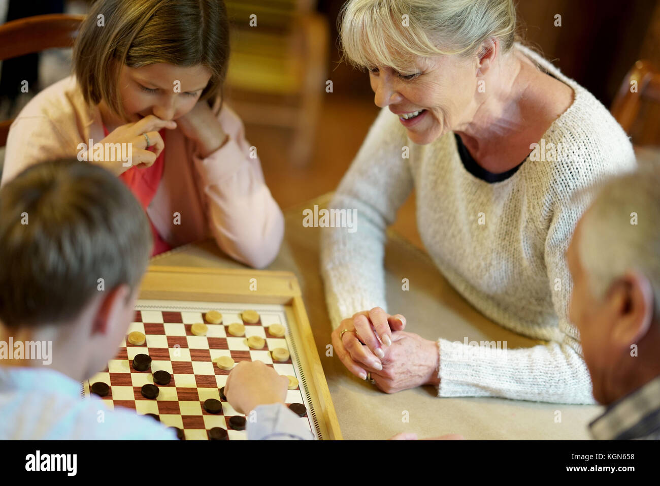 Großeltern mit Enkelkindern spielen Checkers Stockfoto