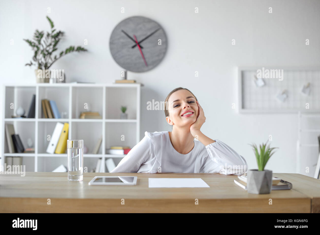 Lächelnd geschäftsfrau am Schreibtisch im Büro Stockfoto