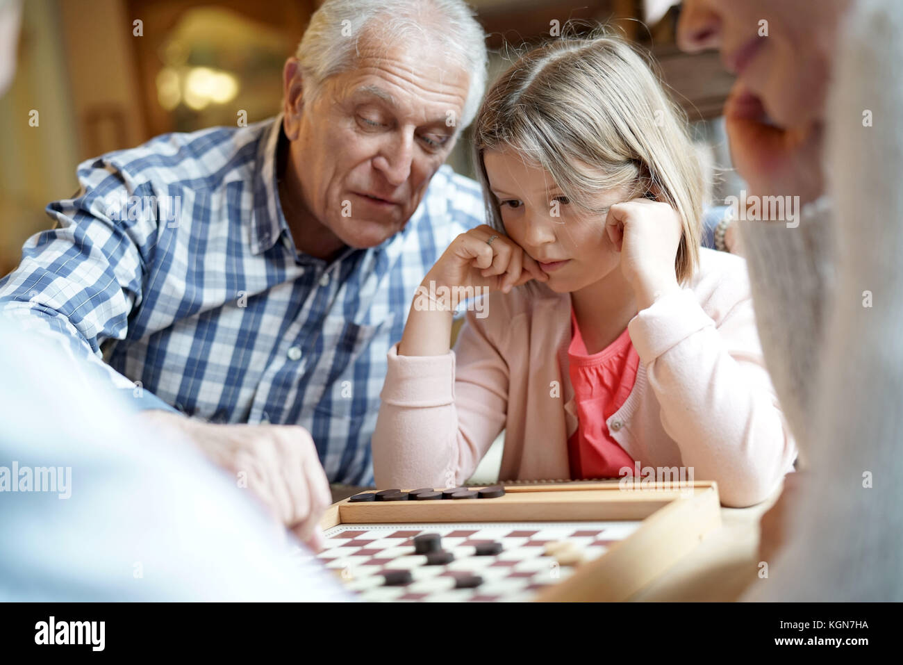 Großeltern mit Enkelkindern spielen Checkers Stockfoto