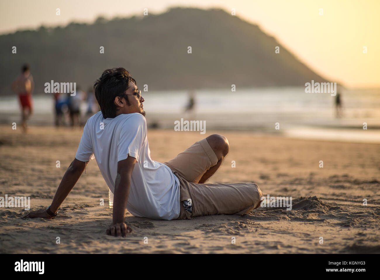 Indische Touristen sitzen auf einem Strand bei Sonnenuntergang. Stockfoto