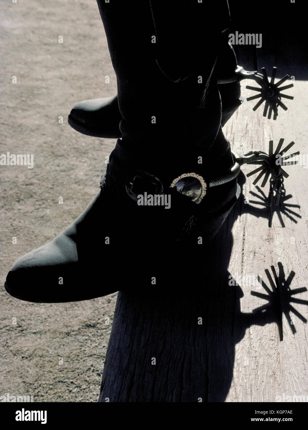 Die spurs aus Metall und Leder Stiefel eines amerikanischen Cowboy sind silhouetted, als er Schritte, eine hölzerne Veranda Schritt bei einer Western Guest Ranch in Arizona, USA. Stockfoto