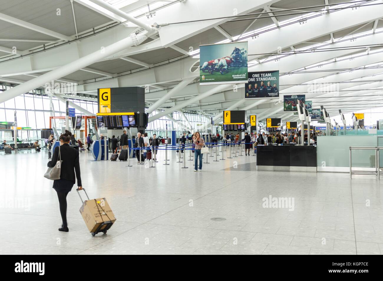 Eine weibliche Passagierin kommt zum Check-in in der Abflughalle in Terminal 5, Flughafen Heathrow Stockfoto