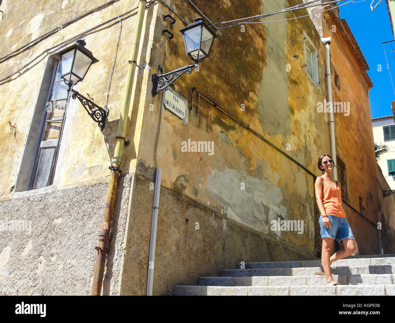 Junge Frau mit Sonnenbrille im lässigen Sommer Kleidung Wandern in einem kleinen ländlichen Dorf in Italien gekleidet Stockfoto