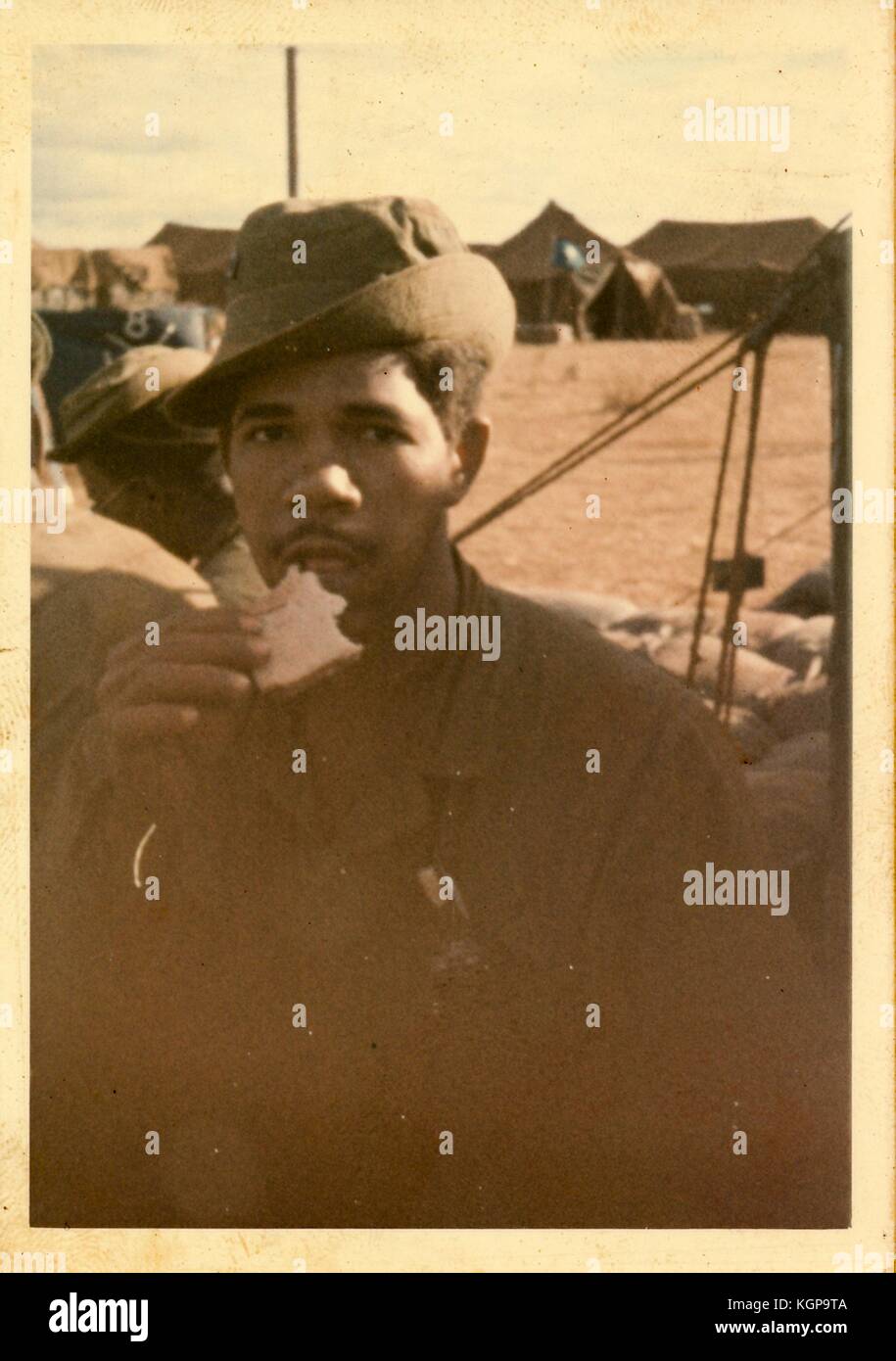 Ehrliches Porträt eines afrikanischen amerikanischen Soldaten essen ein Sandwich unter Zelte an einer amerikanischen Militärbasis in Vietnam während des Vietnam Krieges, 1968. Stockfoto