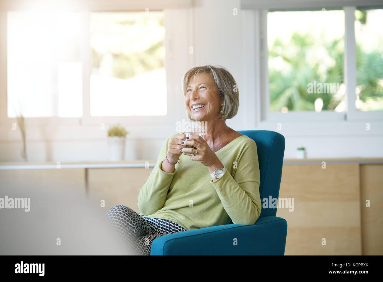 Ältere Frau im Sessel trinken heißen Tee Stockfoto