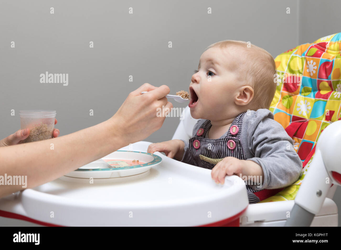 Mutter füttern Sie Ihr Baby mit Löffel voller Brei Stockfoto