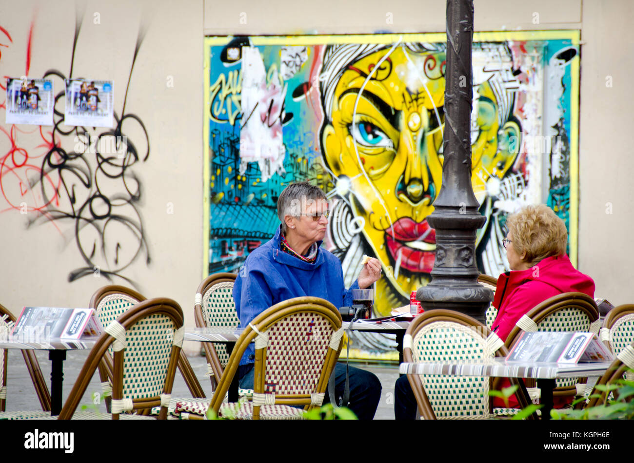 Paris, Frankreich. Zwei Frauen in einem Café sitzen, Edmond Michelet mit Graffiti hinter Stockfoto