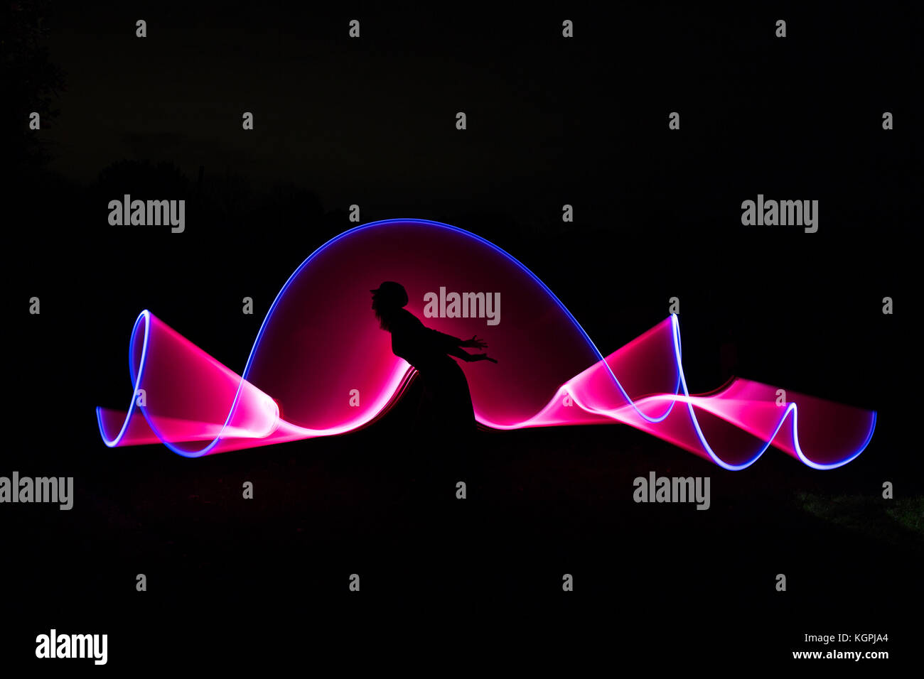Lichtmalerei Fotografie mit Silhouette der isolierten Frau (Seitenansicht) in Blackout-Nacht-Szene. Stockfoto