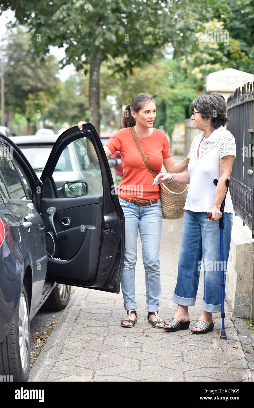 Junge Pflegeperson helfen älteren Frau im Auto Stockfoto