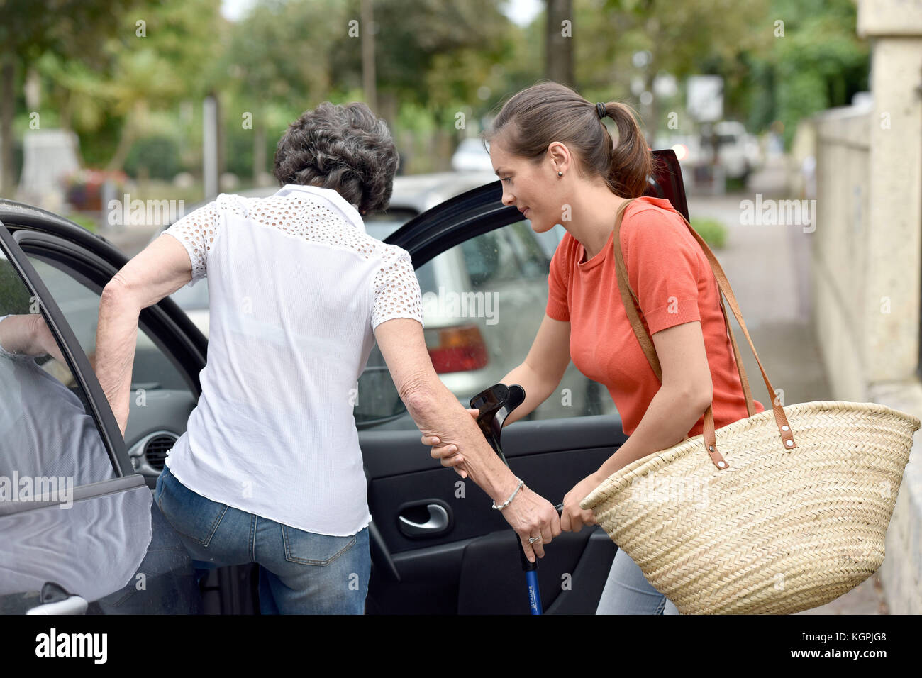 Junge Pflegeperson helfen älteren Frau im Auto Stockfoto