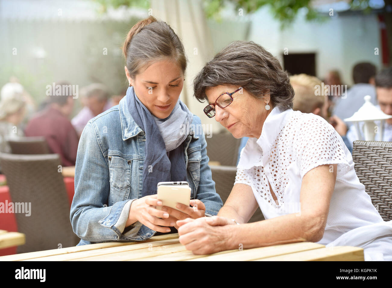 Ältere Frau und Hausfrau auf der Café-Terrasse mit dem Smartphone Stockfoto