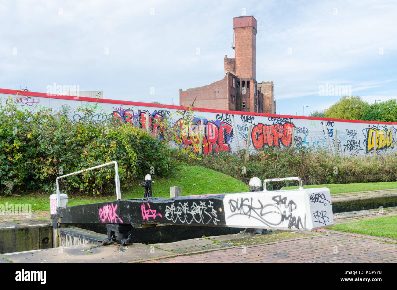 Birmingham Fazeley canal Lock mit Graffiti und Red Brick factory im Hintergrund Stockfoto