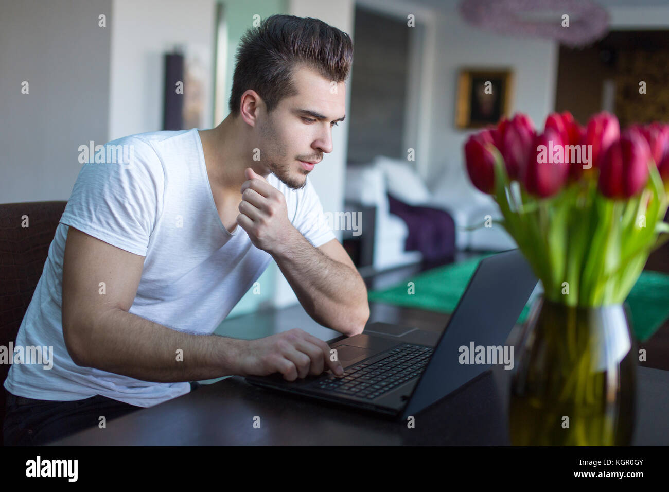 Junge casual kaukasischen Menschen surfen im Internet per Laptop im Innenbereich Stockfoto