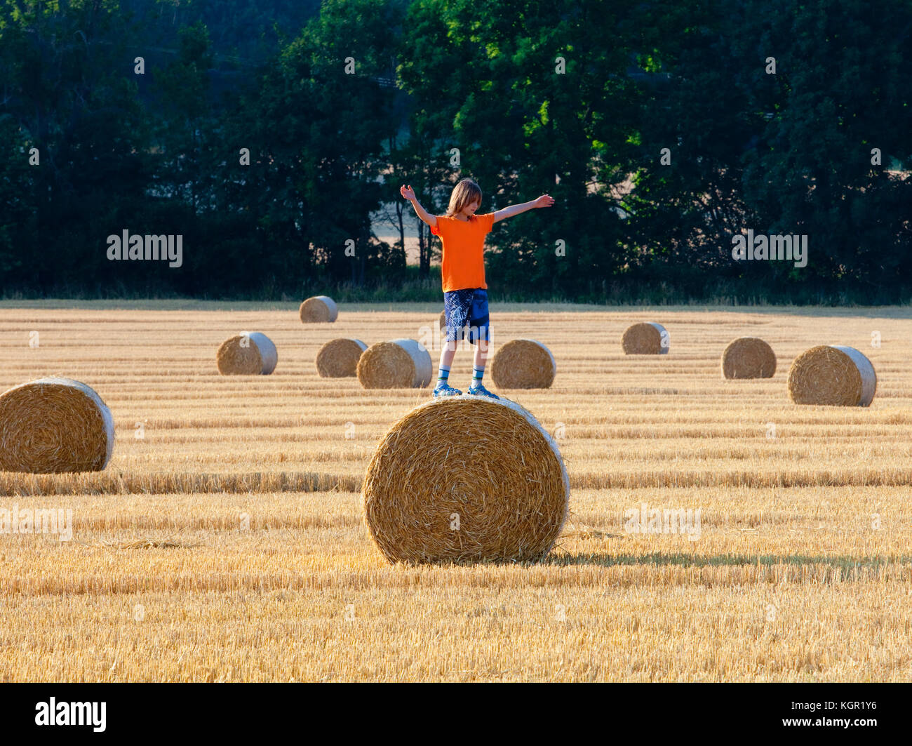 Junge Klettern ein Ballen Heu auf einem Feld im Sommer Stockfoto