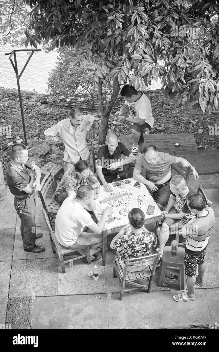 Guilin, China - 14. September 2017: Männer spielen Karten in einem Park von Lijiang River Bank. Stockfoto