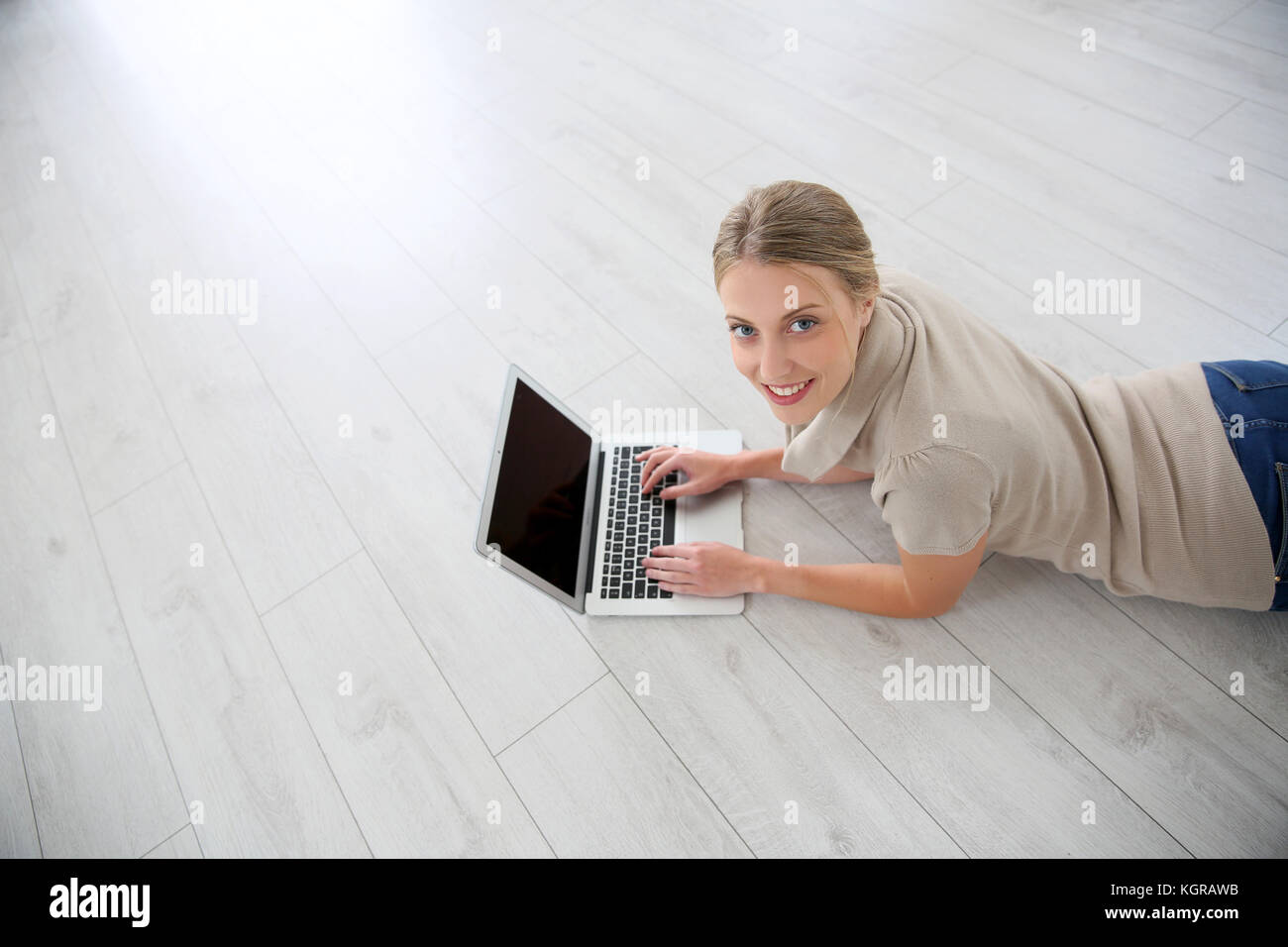 Junge Frau auf Holzböden mit Laptop Stockfoto