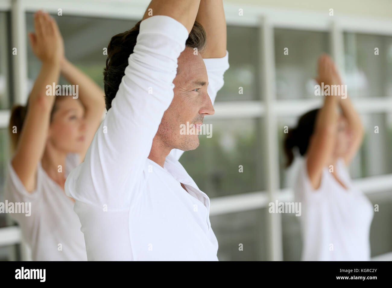 Reifer Mann unter Gruppe Yoga Übungen Stockfoto