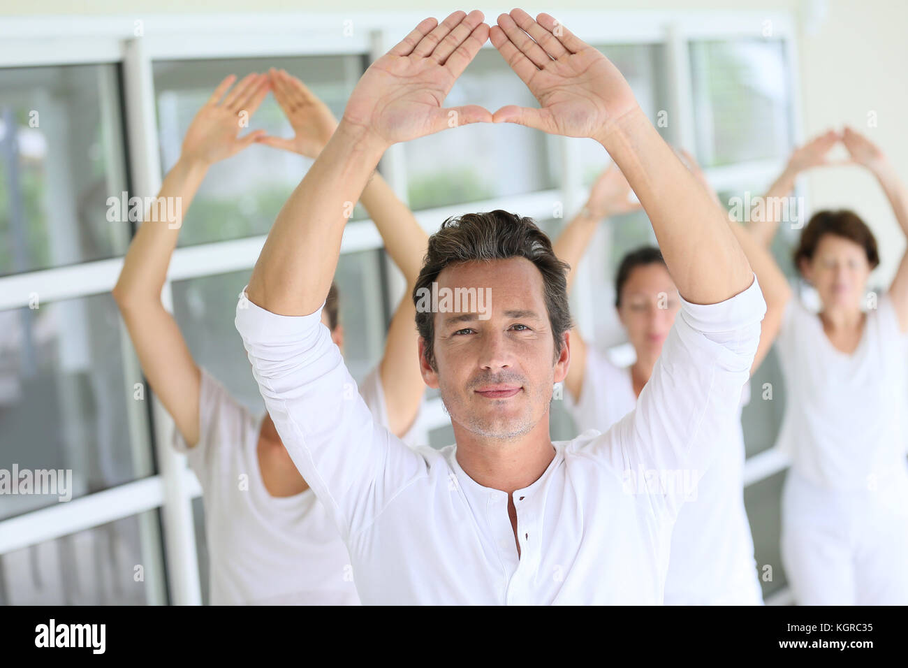 Reifer Mann unter Gruppe Yoga Übungen Stockfoto
