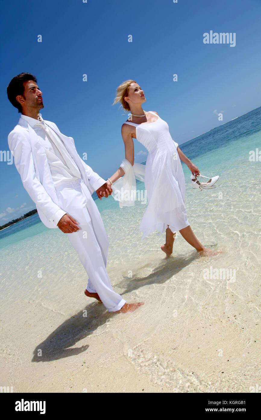 Frisch verheiratete Ehepaar zu Fuß am Sandstrand Stockfoto