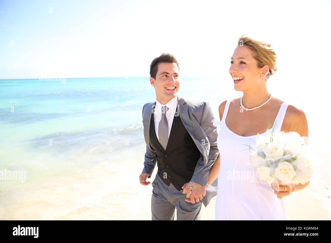 Frisch verheiratete Ehepaar zu Fuß am Strand Stockfoto